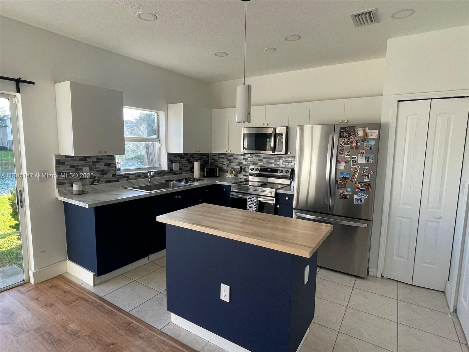1636 Southeast 30th Street, Unit 1636 Homestead, FL 33035 - Photo 10 of 12 a kitchen with kitchen island stainless steel appliances a refrigerator sink stove microwave and cabinets