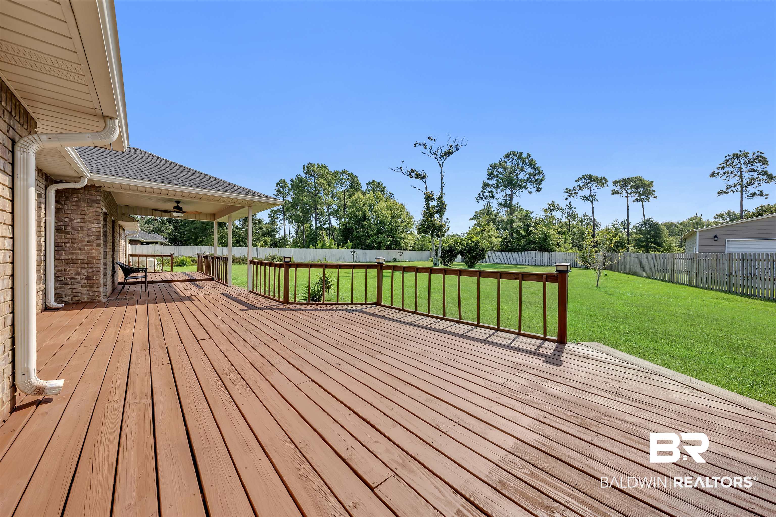 10147 Lyttleton Loop Lillian, AL 36549 - Photo 7 of 29 Expansive wood-finish deck with a wood railing system overlooking a lush green lawn