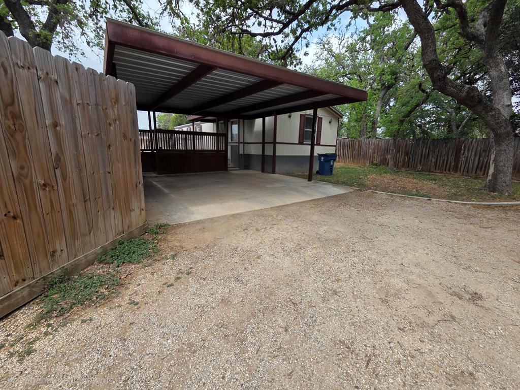 a view of backyard with wooden fence and a large tree