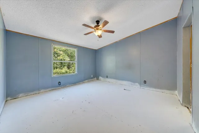 an empty room with windows and ceiling fan