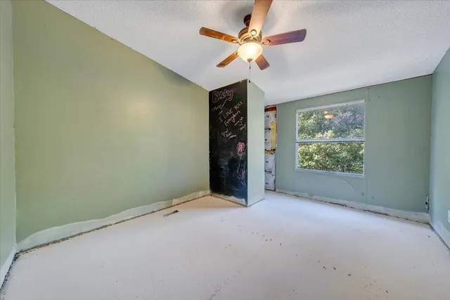 an empty room with windows and fan