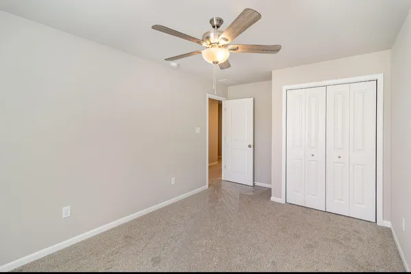 an empty room with closet and a ceiling fan