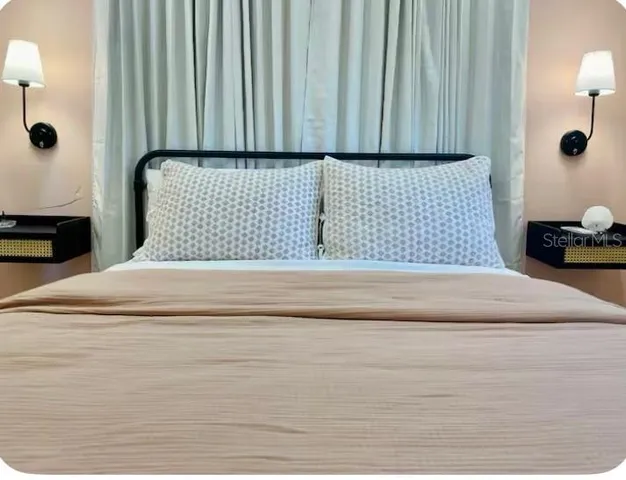 a view of a bedroom with a bed and wooden floor