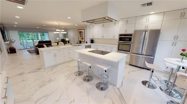 a kitchen with stainless steel appliances kitchen island granite countertop a sink and refrigerator