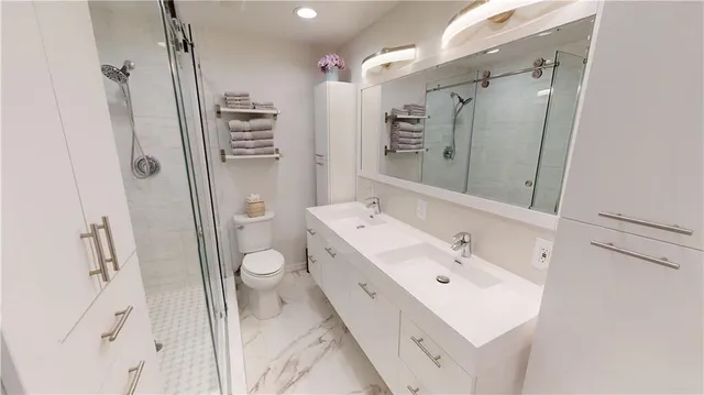 a spacious bathroom with a double vanity sink toilet and shower