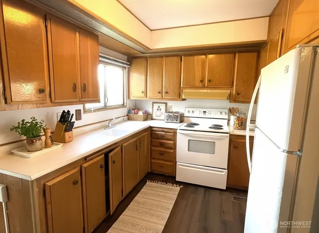 a kitchen with a refrigerator a stove top oven a sink and a window