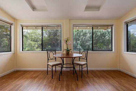 a dining room with wooden floor a chandelier a glass table and chairs
