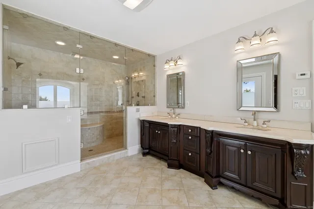 a spacious bathroom with a granite countertop double vanity sink a mirror and bathtub