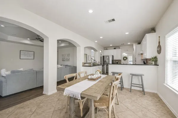 a dining hall with stainless steel appliances kitchen island granite countertop a dining table and chairs