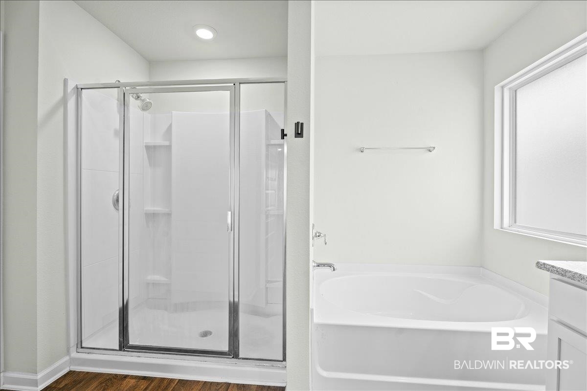 23641 Unbridled Loop Daphne, AL 36526 - Photo 21 of 40 Bathroom featuring a glass-enclosed shower, built-in shower shelving, a separate soaking tub, and a window with frosted glass