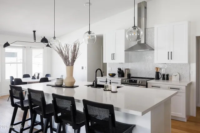 a kitchen with stainless steel appliances a sink a stove and chairs