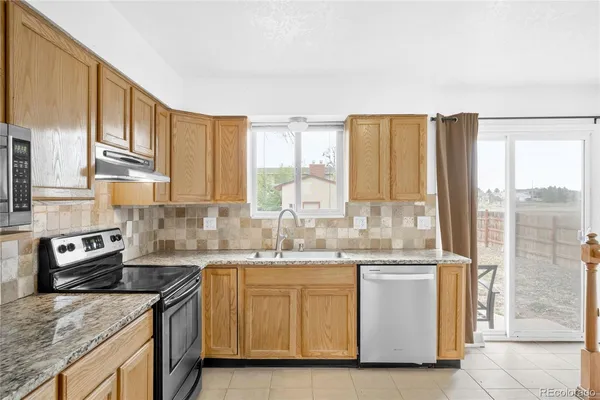 a kitchen with stainless steel appliances granite countertop a sink a stove and a refrigerator