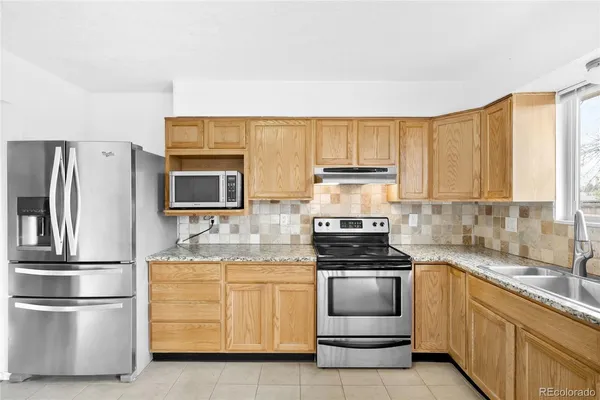 a kitchen with granite countertop a refrigerator stove and sink