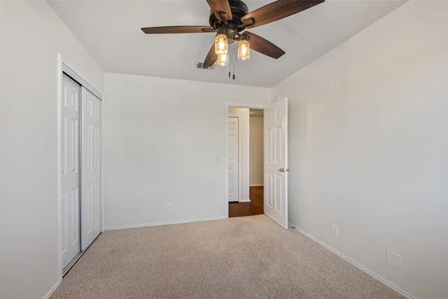 an empty room with closet and a chandelier fan