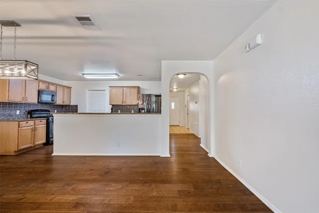 a view of a kitchen with kitchen island wooden floors and stainless steel appliances