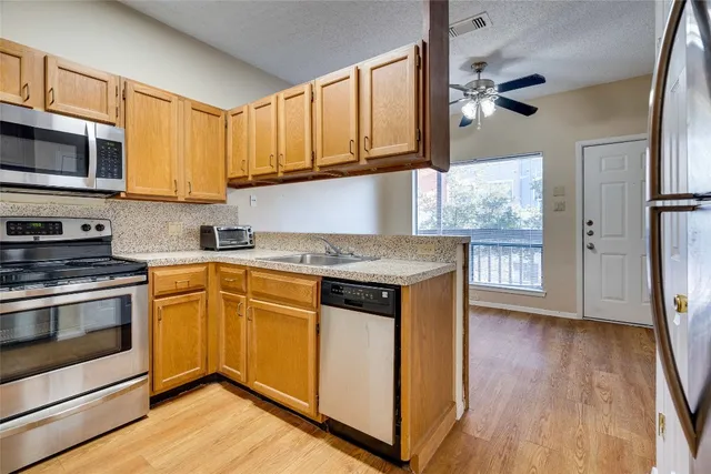 a kitchen with stainless steel appliances granite countertop wooden cabinets a refrigerator and a stove top oven