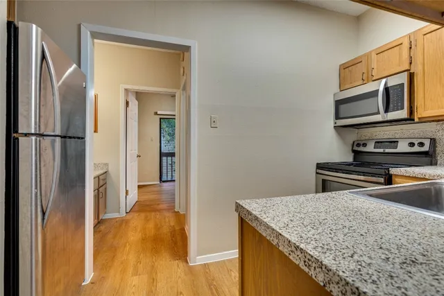 a kitchen with stainless steel appliances granite countertop a refrigerator and a stove top oven