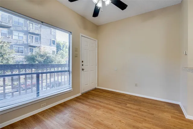 a view of an empty room with wooden floor and a window