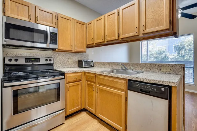 a kitchen with granite countertop wooden cabinets stainless steel appliances and a sink