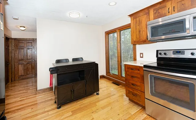a kitchen with stainless steel appliances a stove a microwave and a hard wood floor