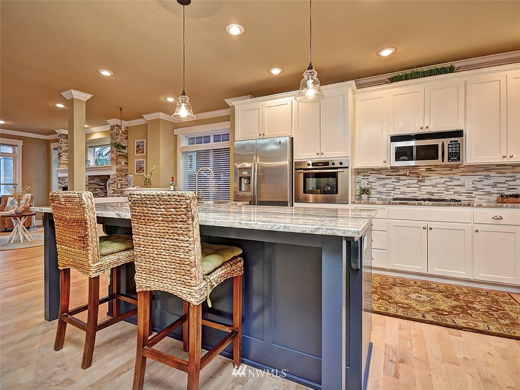 906 North 27th Place Renton, WA 98056 - Photo 4 of 25 a kitchen with stainless steel appliances granite countertop a stove top oven a sink dishwasher a dining table and chairs with wooden floor