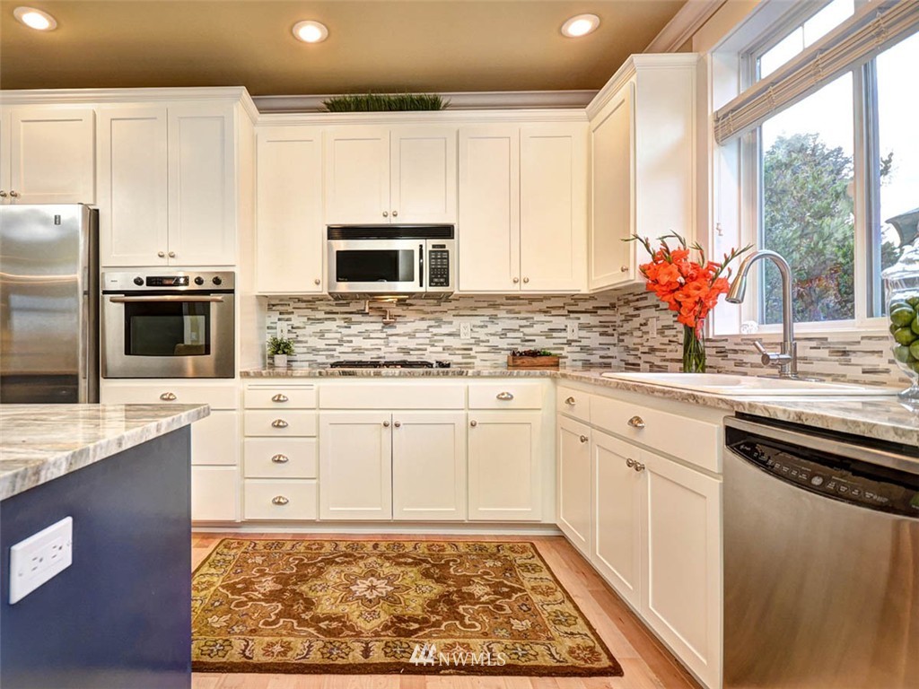 906 North 27th Place Renton, WA 98056 - Photo 5 of 25 a kitchen with stainless steel appliances kitchen island granite countertop a sink stove and cabinets