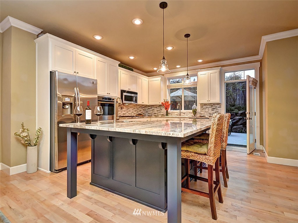 906 North 27th Place Renton, WA 98056 - Photo 6 of 25 a kitchen with stainless steel appliances granite countertop a table chairs and a refrigerator