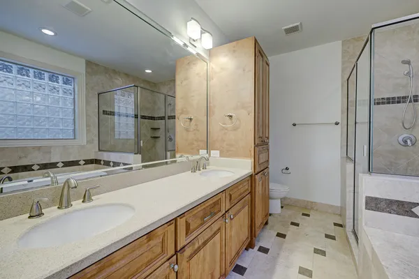 a bathroom with a sink double vanity granite tub shower and a mirror
