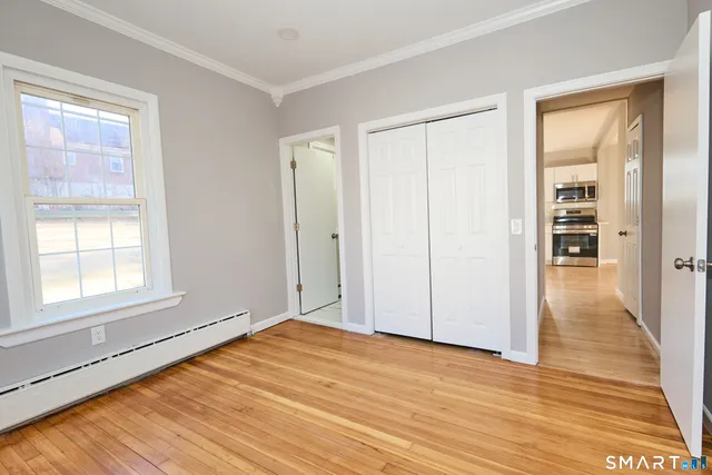 a view of empty room with wooden floor and fan