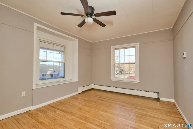 a view of an empty room with a window and wooden floor