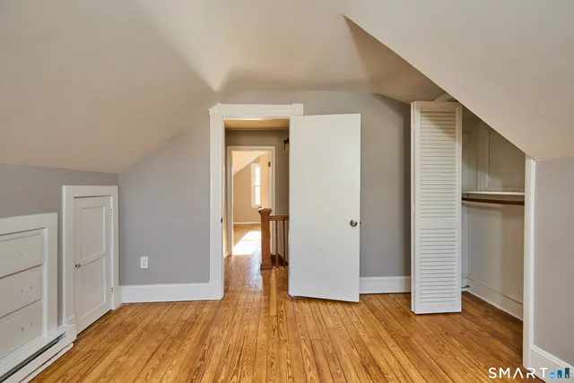 a view of an empty room with wooden floor and closet