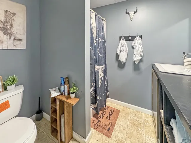 a bathroom with a granite countertop sink a toilet and a shower