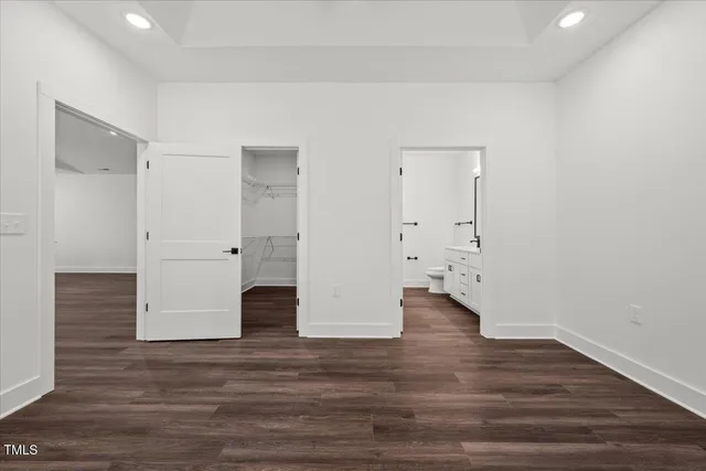 an empty room with wooden floor chandelier and windows