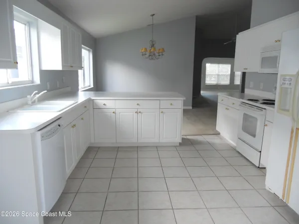 a large white kitchen with a stove a sink dishwasher and a refrigerator