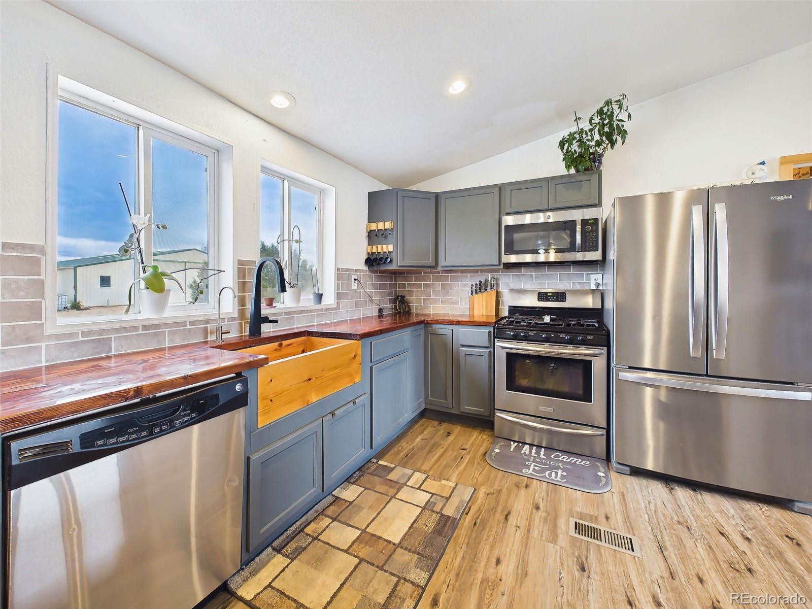 699 Cedar Hills Road Penrose, CO 81240 - Photo 14 of 50 a kitchen with stainless steel appliances granite countertop a refrigerator a sink dishwasher a stove and white countertops with wooden floor