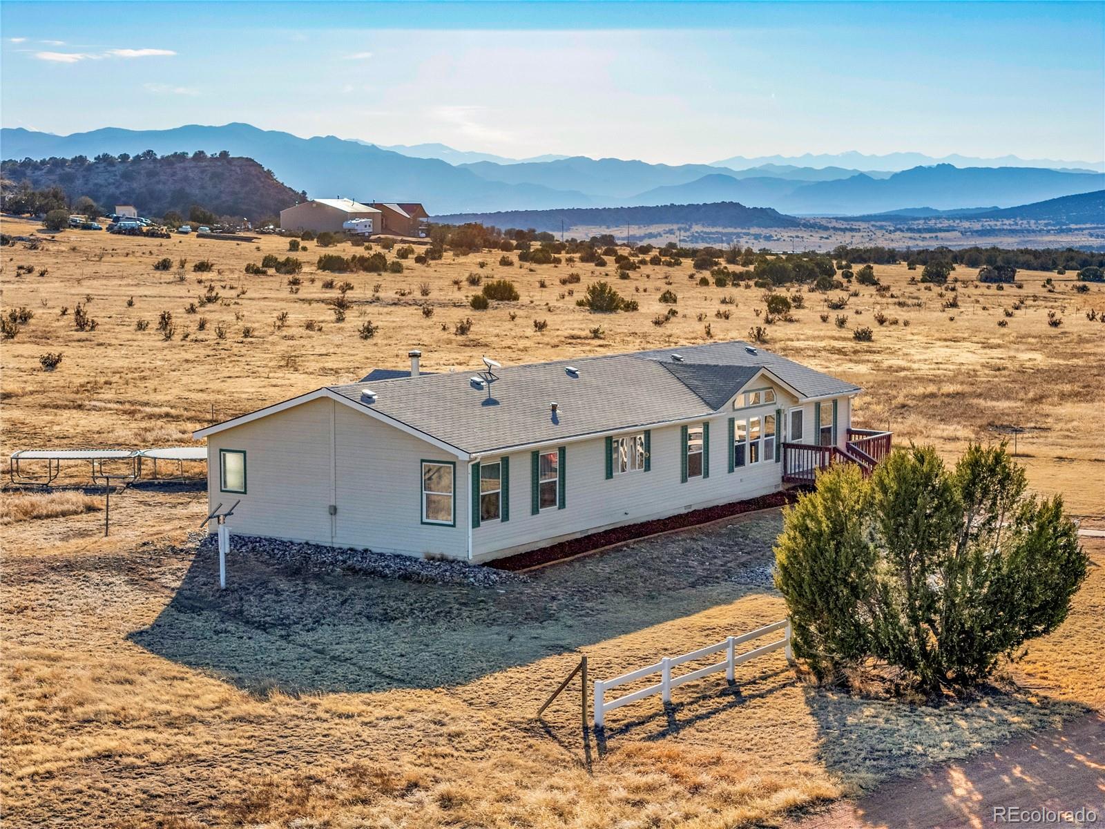 699 Cedar Hills Road Penrose, CO 81240 - Photo 2 of 50 a view of a white house next to a yard and mountain view