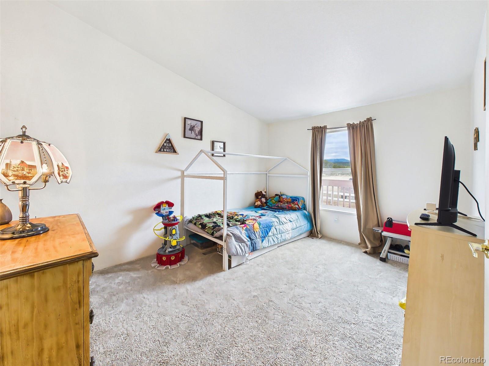 699 Cedar Hills Road Penrose, CO 81240 - Photo 27 of 50 a bedroom with furniture and a flat screen tv