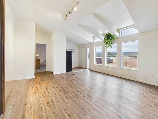 a view of an empty room with a window and wooden floor