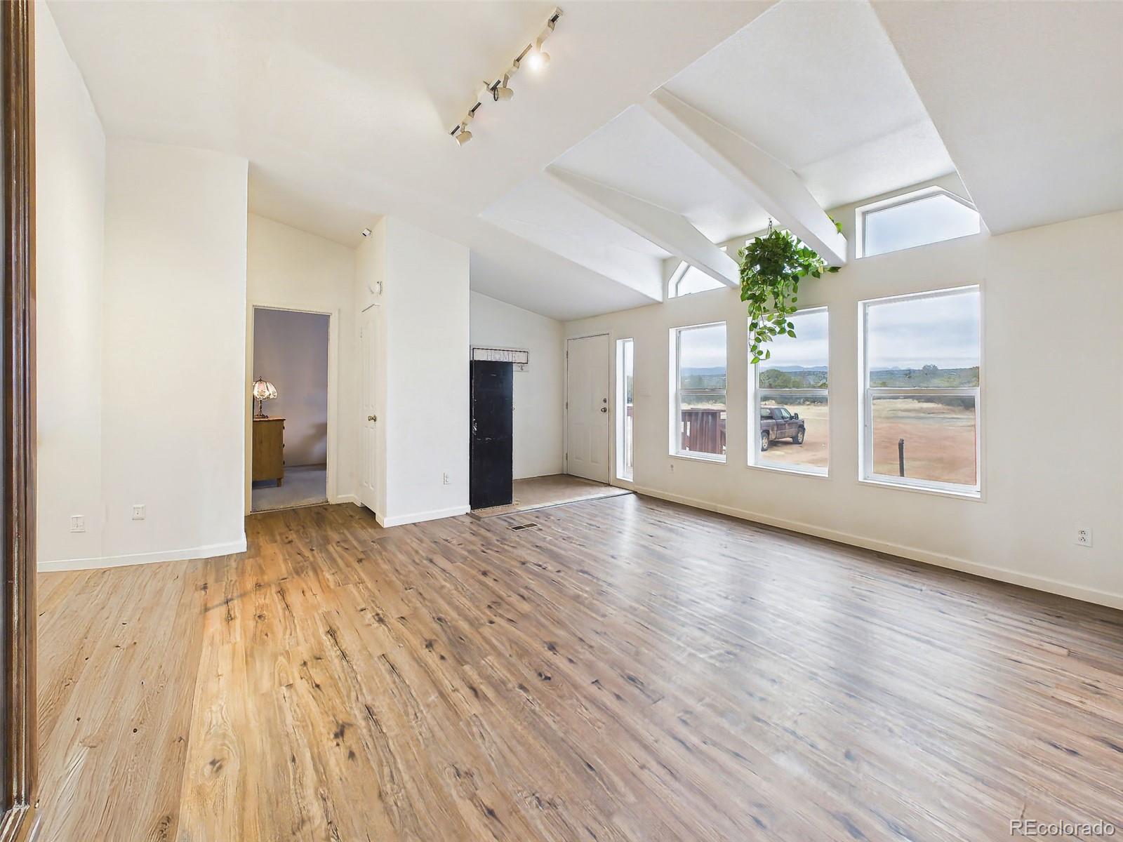 699 Cedar Hills Road Penrose, CO 81240 - Photo 3 of 50 a view of an empty room with a window and wooden floor