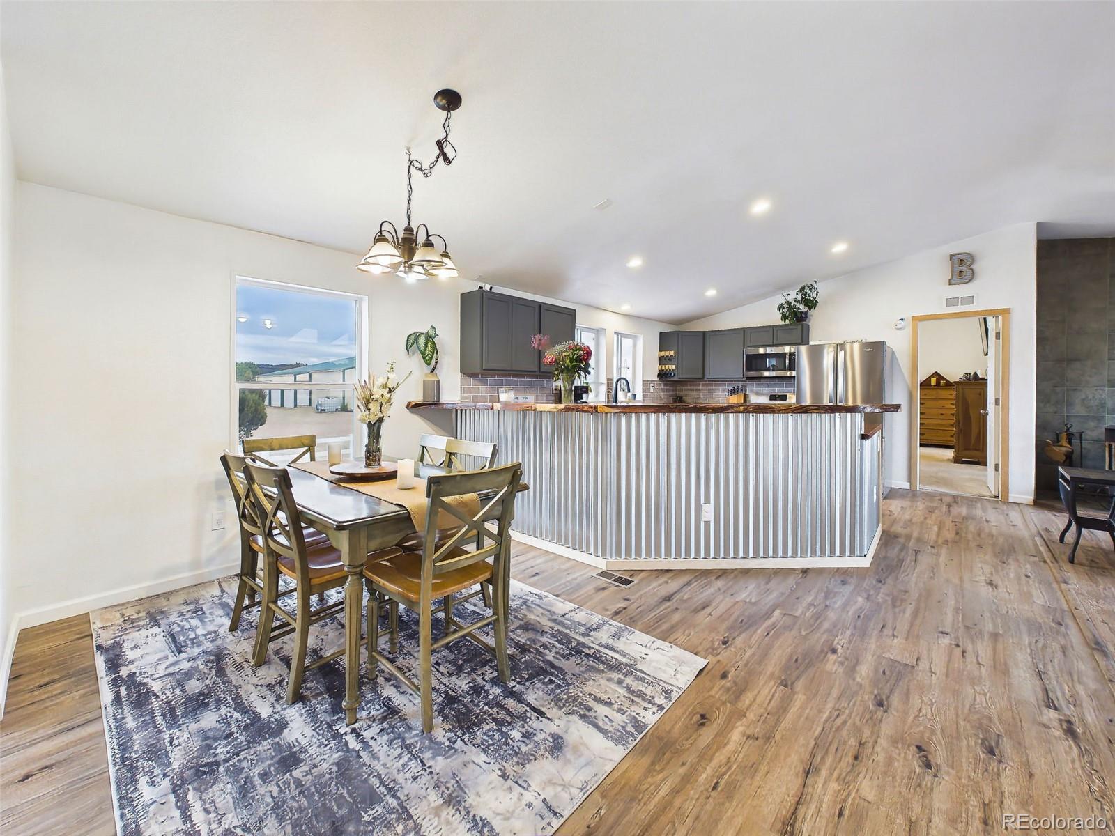 699 Cedar Hills Road Penrose, CO 81240 - Photo 6 of 50 a dining room with wooden floor a chandelier a wooden table and chairs