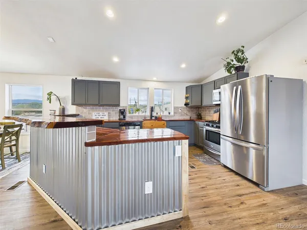 a kitchen with stainless steel appliances granite countertop a refrigerator a stove a sink a microwave and island