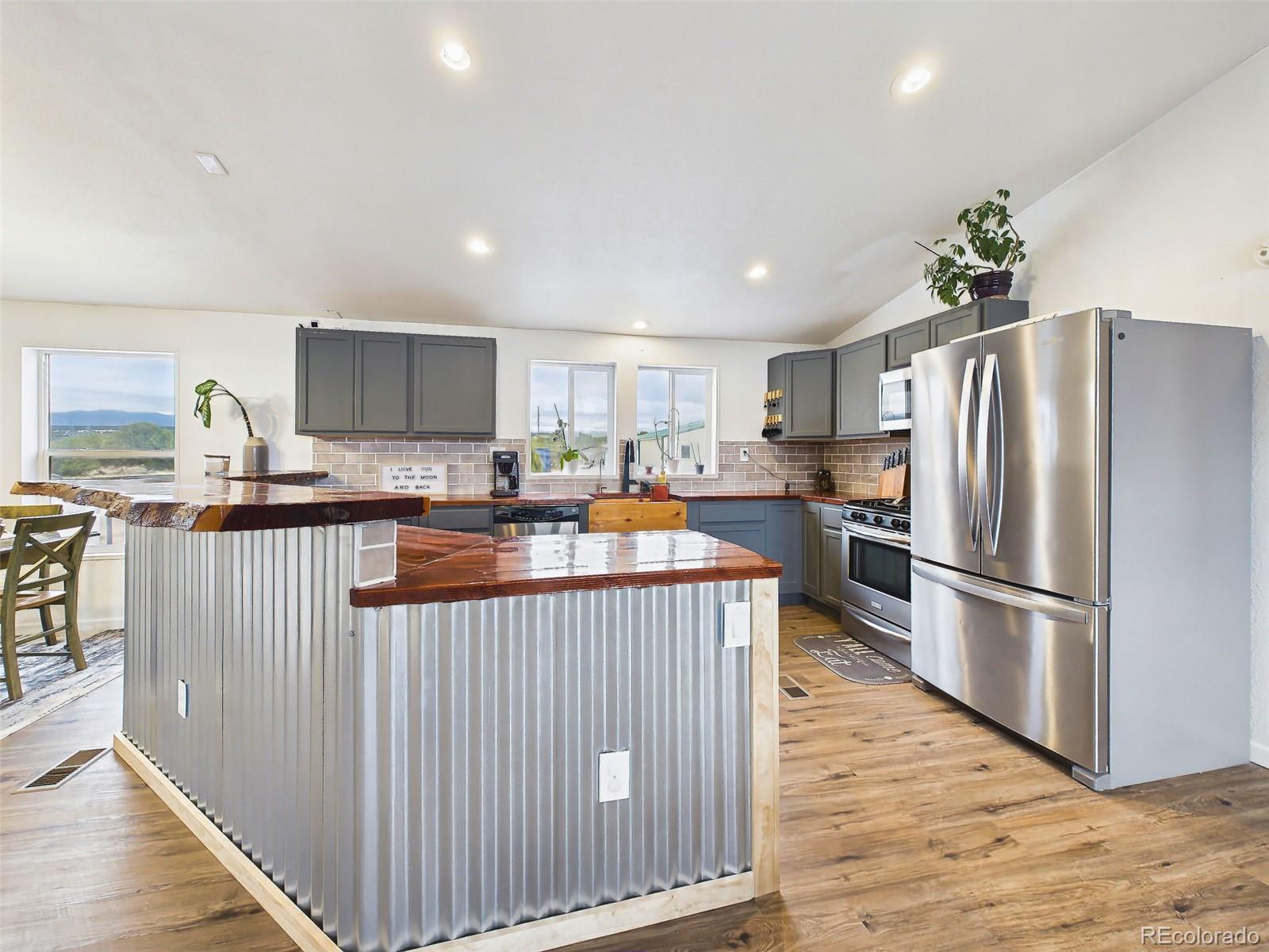 699 Cedar Hills Road Penrose, CO 81240 - Photo 8 of 50 a kitchen with stainless steel appliances granite countertop a refrigerator a stove a sink a microwave and island