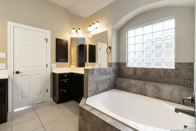 a spacious bathroom with a tub sink and mirror