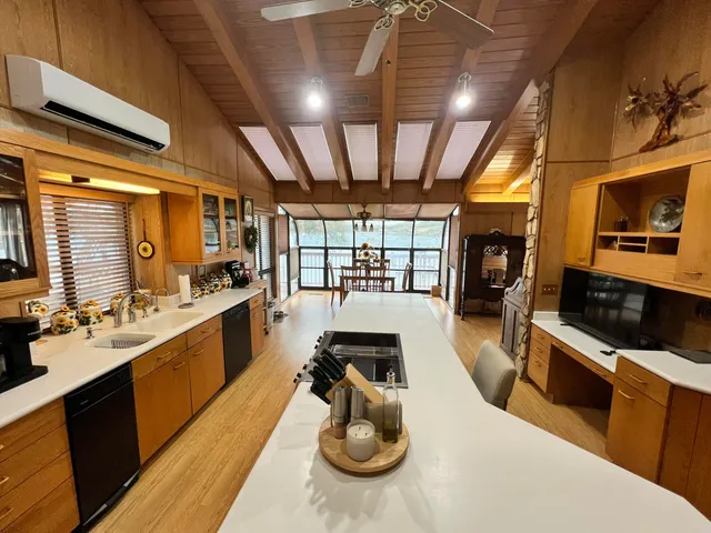 a kitchen with stainless steel appliances a stove a sink dishwasher and a dining table with wooden floor