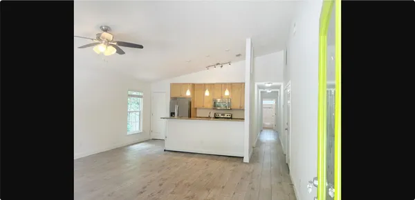 a view of a hallway with wooden floor and a bathroom