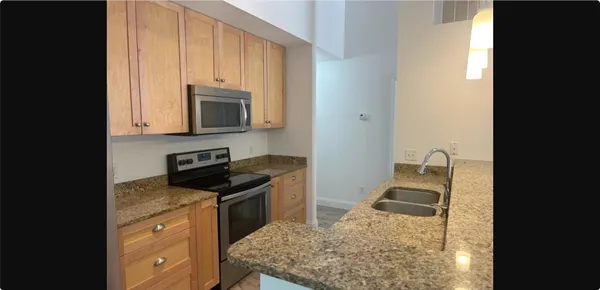 a kitchen with stainless steel appliances granite countertop a stove a sink and a microwave