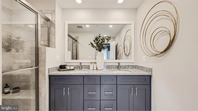 a bathroom with a granite countertop double vanity sink and a mirror