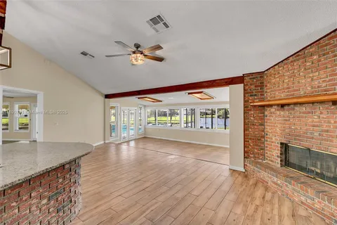 a view of an empty room with wooden floor fireplace and a window