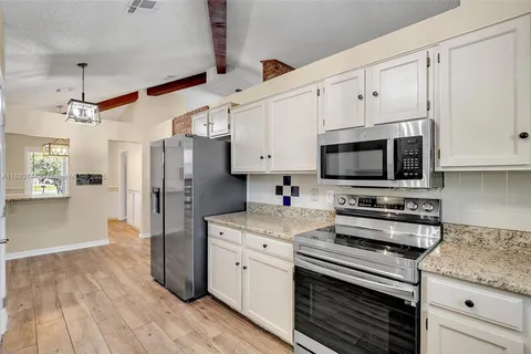 a kitchen with stainless steel appliances white cabinets and a stove top oven