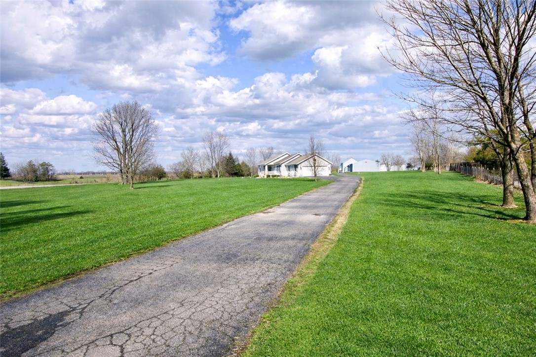 1000 Stone Road Xenia, OH 45385 - Photo 30 of 39 A long paved driveway leads to a charming house, surrounded by lush green lawns and mature trees.